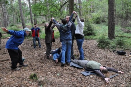 Bild 1: Joseph Cornell (vorne links) verwandelte einige Teilnehmer des Workshops in einen Baumriesen. Als Wurzel, Kernholz oder Borke empfinden sie gemeinsam die verschiedenen Prozesse innerhalb eines Baumes nach. Foto: Dr. Gertrud Hein (NUA)