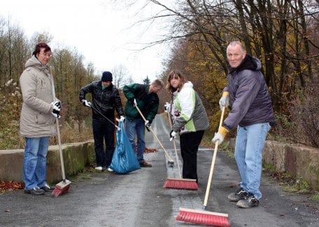 Bild 1: Menschen mit Behinderung helfen Menschen mit Behinderung: Mit Spaß kehren freiwillige Helfer der Lebenshilfe Kall das Blindenleitsystem im Barrierefreien Natur-Erlebnisraum Wilder Kermeter frei.