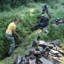 Bild 2: Die Helfer des Bergwaldprojektes tragen die Steine ab und entfernen damit die Ufer- und Sohlbefestigungen des Sauerbaches im Nationalpark Eifel. Foto: Nationalparkverwaltung