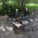 Bild 2: Markus Vollmer vom Bundesforstbetrieb Rhein-Weser (links) und Eckhard Jäck, Leiter der Holzbauwerkstatt der Nationalparkverwaltung (rechts) testen die neuen, naturbelassenen Trittsteine im erfolgreich renaturierten Bachbett des Sauerbachs. (Foto: 